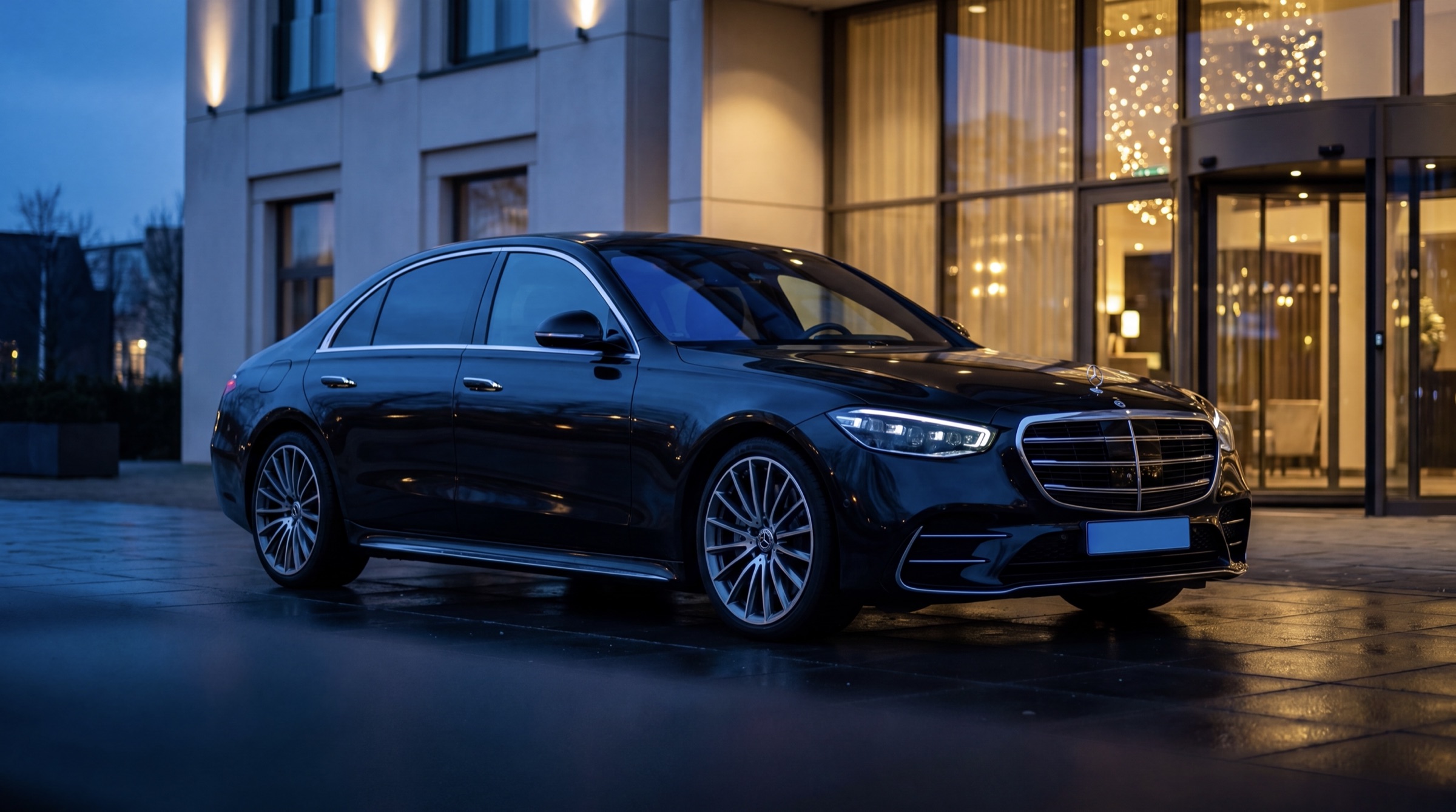 Mercedes S-Klasse wacht bij een luxe hotelentree in de schemering — chauffeur per uur